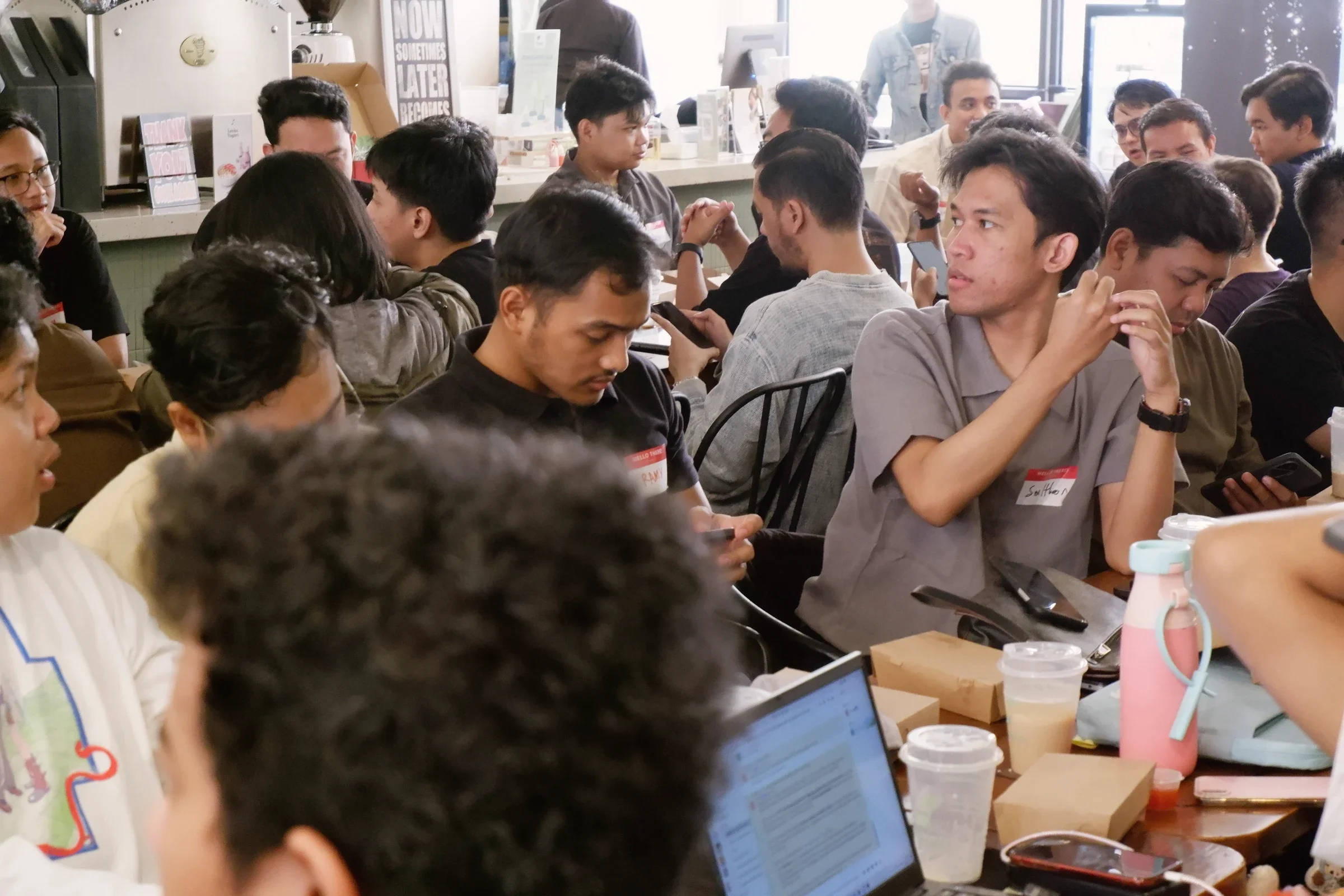 Meetup participants seated closely around a table with laptops and drinks