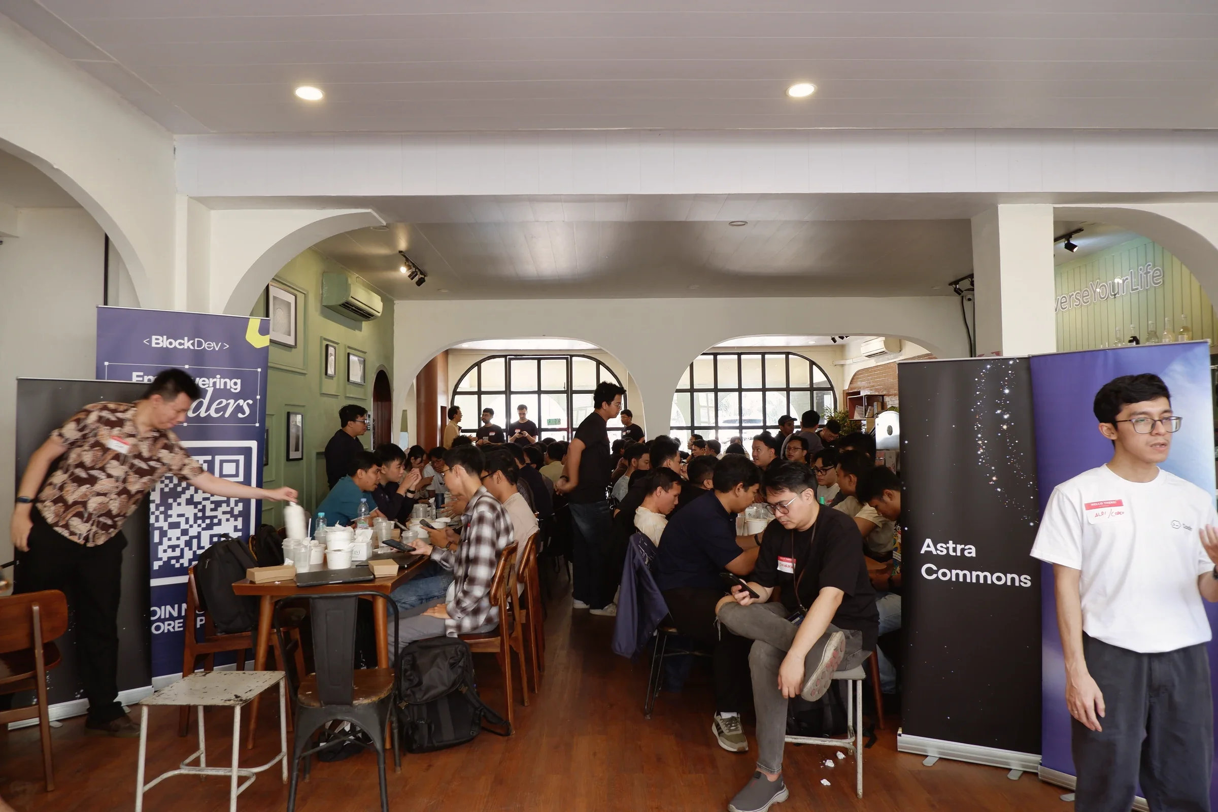 Participants filling the meetup room beside an Astra Commons banner