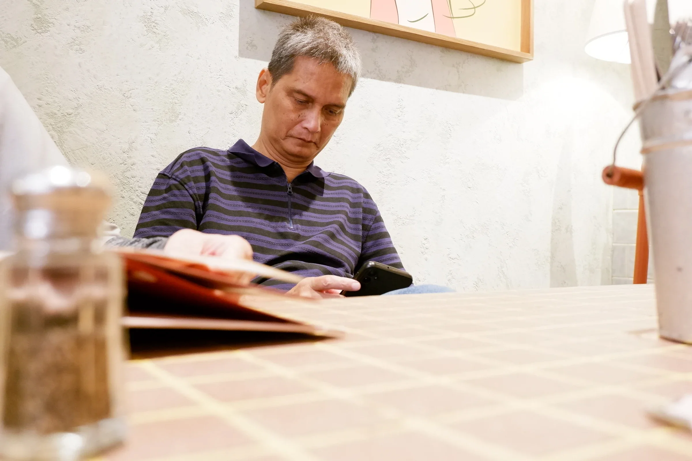 A man in a purple striped shirt seated at a cafe table